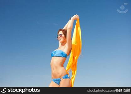 picture of happy woman with yellow sarong on the beach.