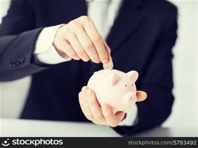 picture of man putting coin into small piggy bank