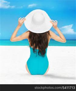 picture of model posing in swimsuit with hat on the beach
