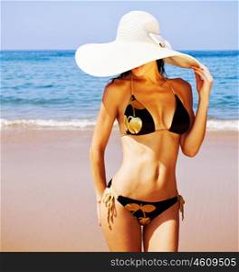 Picture of perfect female on sea coast, young sexy lady in white stylish hat on the beach, seductive woman wear fashionable black swimwear, tanning girl near ocean, tropical resort, summer holiday&#xA;&#xA;