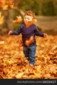 Picture of pretty baby boy running in autumnal park, little child playing with old dry trees foliage, adorable toddler play game on backyard, enjoying walk, beauty autumn season, happy childhood&#xA;&#xA;&#xA;
