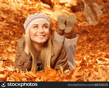 Picture of pretty cheerful woman lay down on the ground covered dry autumnal foliage, cute young lady having fun in fall park, beautiful female rest on backyard, happiness and fun concept&#xA;