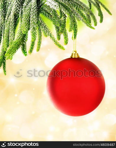 Picture of red Christmastime bubble hanging on fresh green fir branch, holiday decorations isolated on yellow blur background, decorated Christmas tree, New Year ornament, festive glass ball