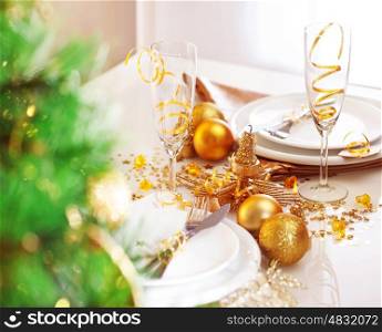 Picture of romantic holiday dinner, luxury table setting and decorated Christmas tree in the restaurant, two glasses for traditional New Year alcohol drink, champagne, xmas white utensil