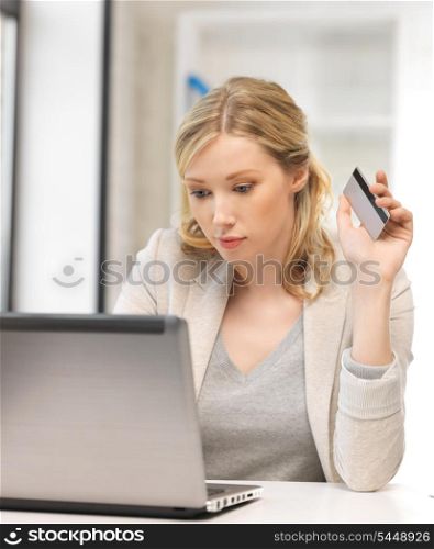 picture of serious woman with laptop computer and credit card.