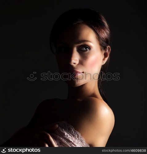 Picture of sexy young lady isolated on black background, stylish woman with dark hair wearing seductive lace dress, pretty female in pink openwork with naked shoulder, sensuality and beauty concept