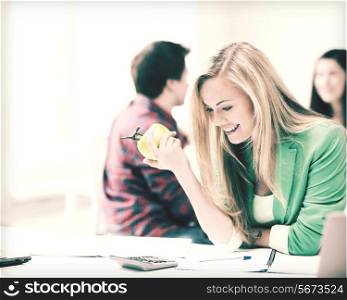 picture of smiling student girl eating apple at school