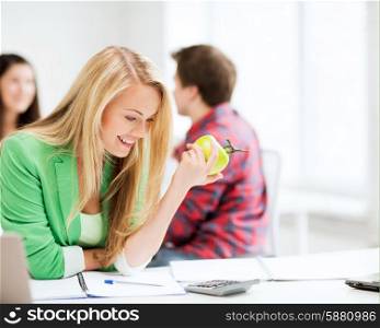 picture of smiling student girl eating apple at school