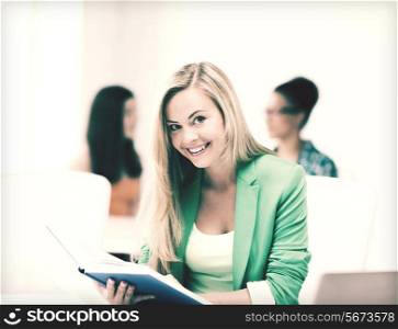 picture of smiling student girl reading book at school