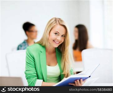 picture of smiling student girl reading book at school