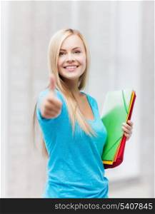 picture of smiling student with folders showing thumbs up