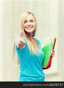 picture of smiling student with folders showing thumbs up. smiling student with folders