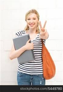 picture of smiling teenage girl with laptop showing victory sign