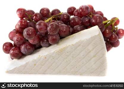 Picture of some grapes in the background, and a slice of brie on the foreground