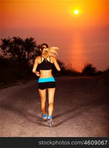 Picture of sporty blond female running along the road over sunset, beautiful active woman doing fitness exercise outdoors, rear view of healthy jogger girl wearing sports clothes, healthy lifestyle