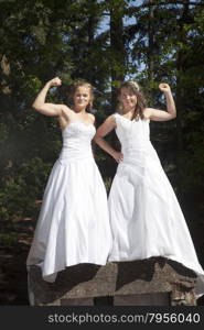 picture of two brides flexing their muscles on concrete object in nature surroundings