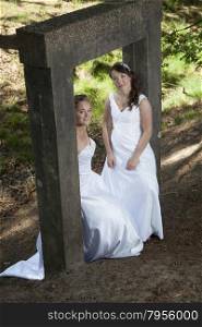 picture of two brides under old concrete object in nature surroundings
