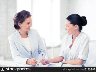 picture of two businesswomen having discussion in office. two businesswomen having discussion in office