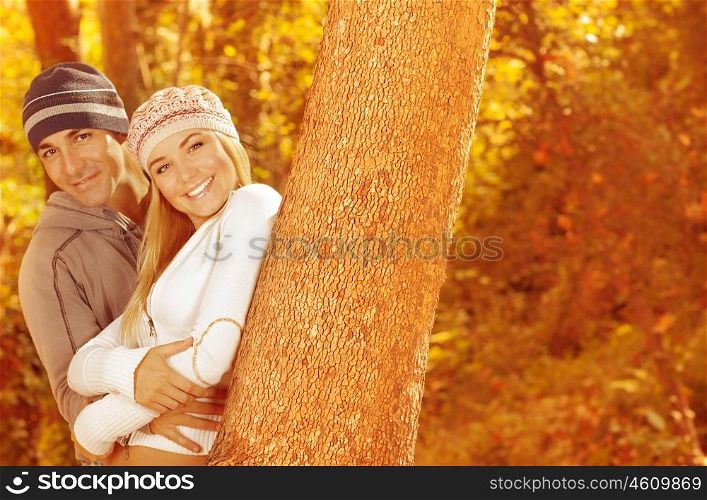 Picture of two happy people spending time together in beautiful autumn woods, closeup portrait of attractive female with handsome male standing near tree over golden trees foliage &#xA;