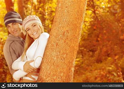 Picture of two happy people spending time together in beautiful autumn woods, closeup portrait of attractive female with handsome male standing near tree over golden trees foliage &#xA;