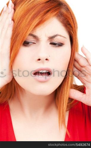 picture of unhappy redhead woman with hands on ears