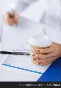 picture of woman hand filling in blank paper and drinking coffee