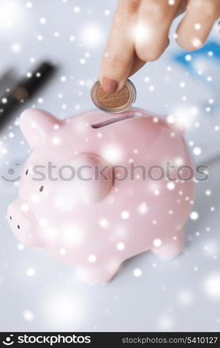 picture of woman hand putting coin into small piggy bank