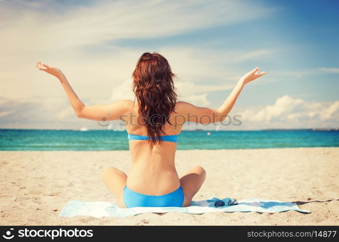 picture of woman practicing yoga lotus pose on the beach