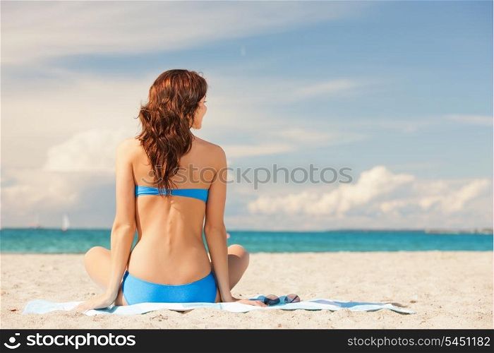 picture of woman practicing yoga lotus pose on the beach.