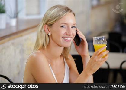 picture of woman talking on cellphone holding juice