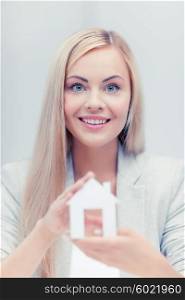 picture of young woman holding white paper house. woman holding paper house
