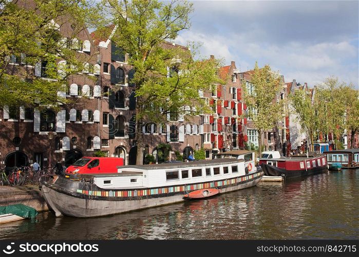 Picturesque Brouwersgracht canal with barge houseboats and historic apartment buildings in Amsterdam, Netherlands.