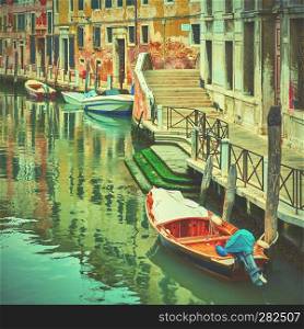 Picturesque canal with moored boats in Venice, Italy. Vintage style toned image