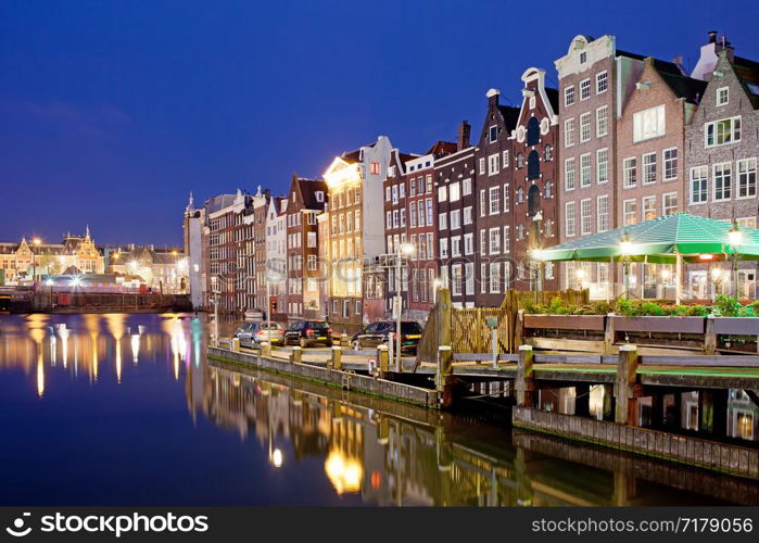 Picturesque city of Amsterdam in Holland, Netherlands at night with historic Dutch style row houses by the canal.