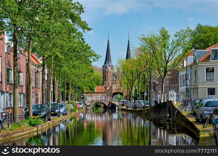 Picturesque Delft cityscape view with Eastern Gate Oostport and canal with cars and bicycles parked along. Delft, Netherlands&rsquo;s. Delft cityscape view with Eastern Gate Oostport and canal with cars and bicycles parked along