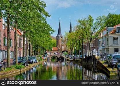 Picturesque Delft cityscape view with Eastern Gate Oostport and canal with cars and bicycles parked along. Delft, Netherlands&rsquo;s. Delft cityscape view with Eastern Gate Oostport and canal with cars and bicycles parked along