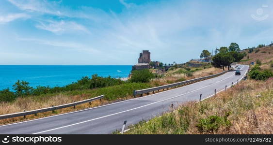 Picturesque historical fortification tower between regional road and beach on Ionian sea coast, South Italy