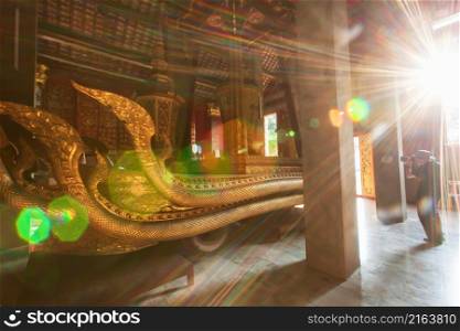Picturesque interiors of the ancient Buddhist temple of Wat Xieng Thong, sunset shines through window on the royal chariot. Luang Prabang, Laos.