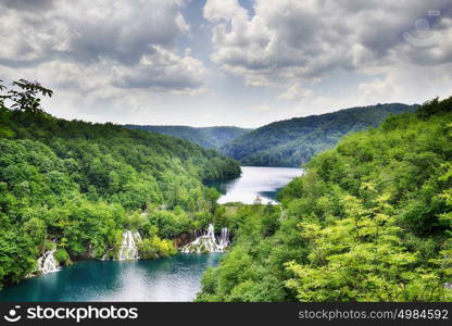 picturesque lake in forest high in mountains with waterfalls