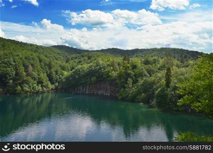 picturesque lake in forest high in mountains with waterfalls