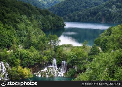 picturesque lake in forest high in mountains with waterfalls