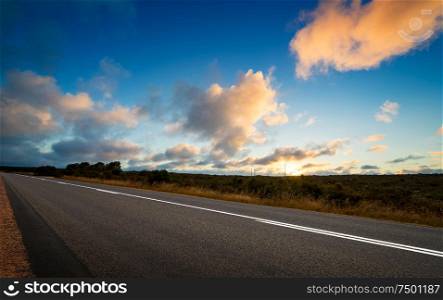 Picturesque landscape scene and sunset above road