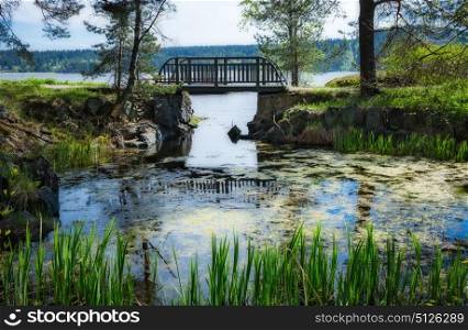 Picturesque landscape with a bridge in a park on the shore of a lake in Karelia