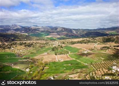 Picturesque landscape with cultivated fields and green meadows of hilly Andalusia countryside in southern Spain.