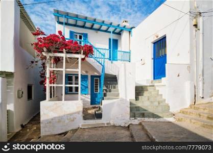 Picturesque narrow street with traditional whitewashed houses with blooming bougainvillea flowers of Naousa town in famous tourist attraction Paros island, Greece. Picturesque Naousa town street on Paros island, Greece