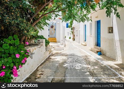 Picturesque narrow street with traditional whitewashed houses with blooming flowers of Naousa town in famous tourist attraction Paros island, Greece. Picturesque Naousa town street on Paros island, Greece