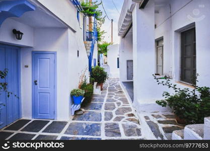 Picturesque narrow street with traditional whitewashed houses with blooming flowers of Naousa town in famous tourist attraction Paros island, Greece. Picturesque Naousa town street on Paros island, Greece