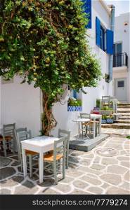 Picturesque narrow street with traditional whitewashed houses with cafe tables of Naousa town in famous tourist attraction Paros island, Greece. Picturesque Naousa town street on Paros island, Greece