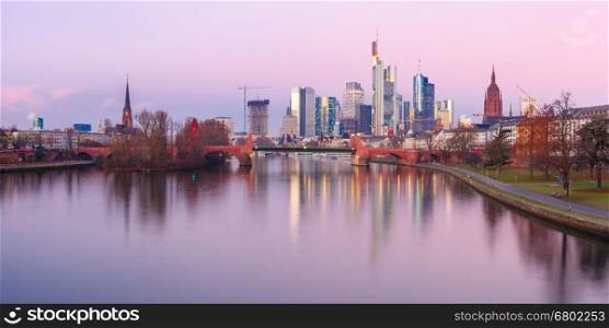 Picturesque panoramic view of business district with skyscrapers and mirror reflections in the river at sunrise, Frankfurt am Main, Germany