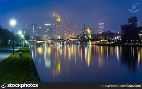 Picturesque panoramic view of Frankfurt am Main skyline during evening blue hour with mirror reflections in the river, Germany